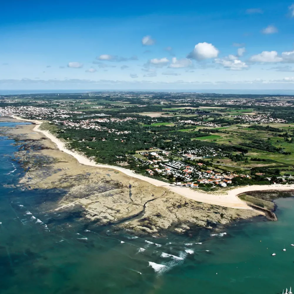Vue aérienne de la côte française avec plages et bateaux.